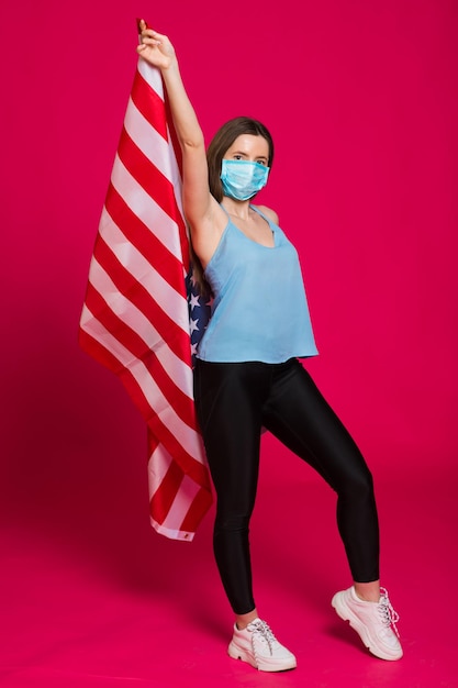Giovane donna che indossa una maschera facciale con bandiera USA su sfondo rosso
