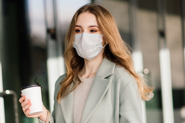 Giovane donna che indossa una maschera per prevenire il virus con le borse della spesa su una strada stretta in Europa.