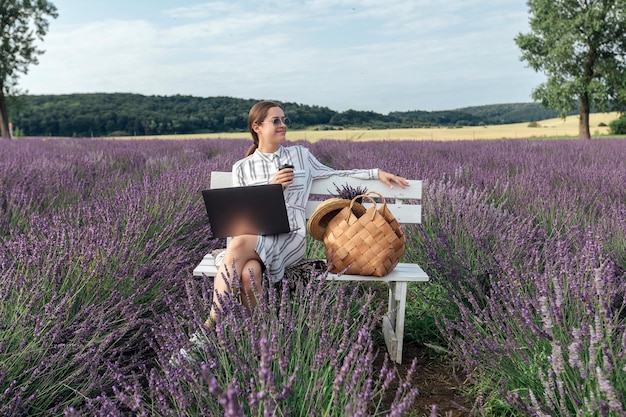 Giovane donna che lavora al computer nel campo di lavanda