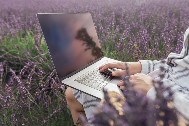 Giovane donna che lavora al computer nel campo di lavanda