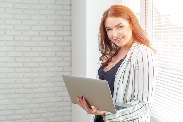 Giovane donna che lavora al computer portatile in ufficio.