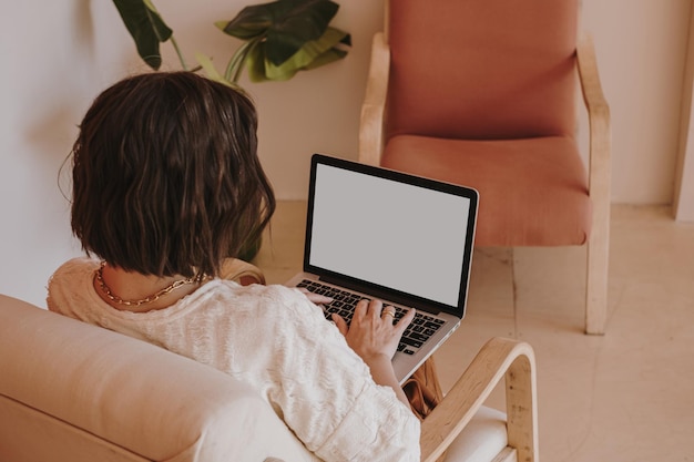 Giovane donna che lavora al computer portatile seduto sulla sedia Lavora a casa al concetto di libero professionista in quarantena Ragazza capo signora capo affari composizione per blog web social media