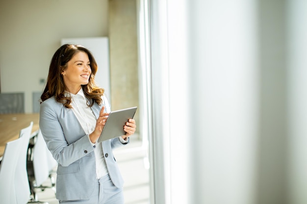 Giovane donna che lavora alla tavoletta digitale dalla finestra dell'ufficio