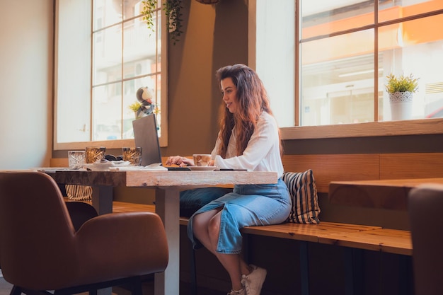 Giovane donna che lavora da un ristorante con il suo laptop