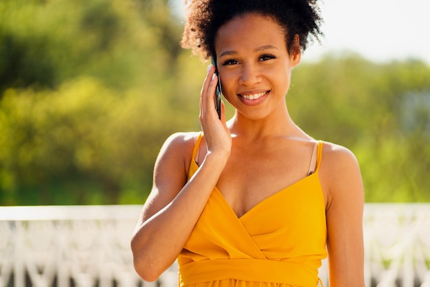 Giovane donna che lavora sorridente parlando al telefono Aspetto afroamericano e riccio nero