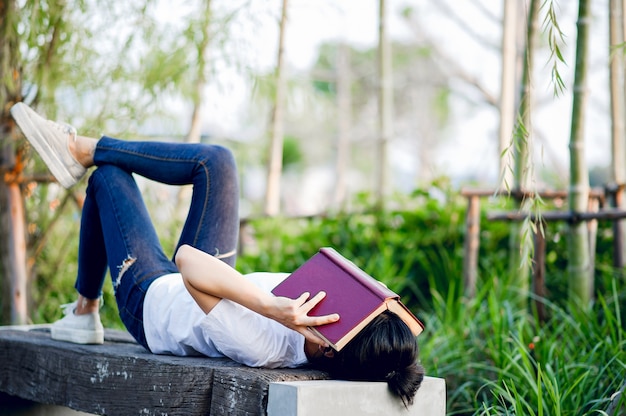 Giovane donna che legge felicemente il libro in natura