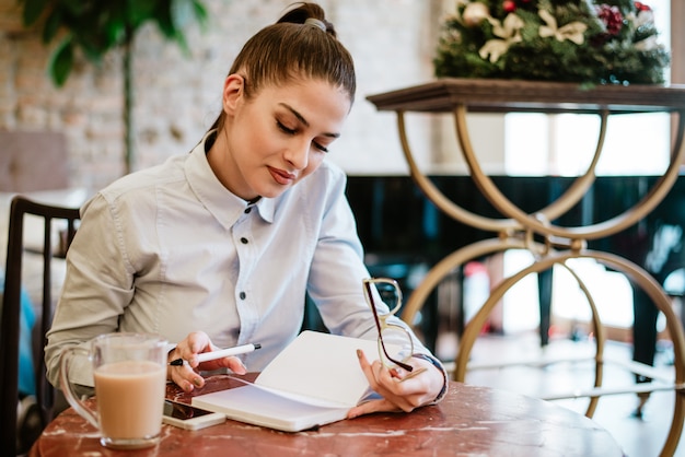 Giovane donna che legge nel caffè.