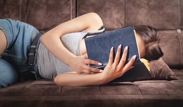 Giovane donna che legge un libro a casa.