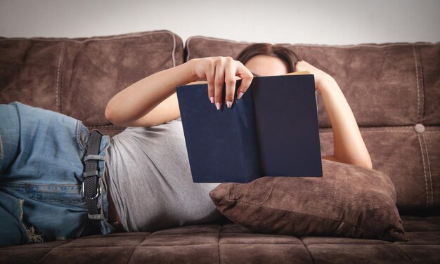 Giovane donna che legge un libro a casa.