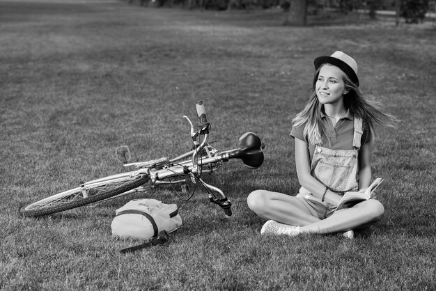 Giovane donna che legge un libro dopo aver pedalato nel parco locale
