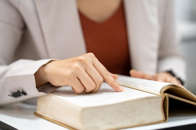 Giovane donna che legge un libro in biblioteca all'università