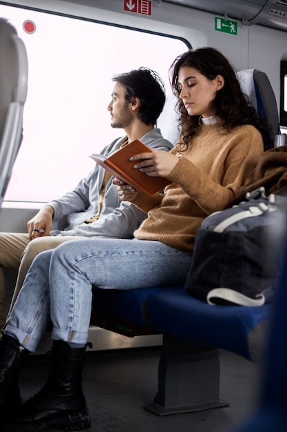 Giovane donna che legge un libro mentre viaggia in treno