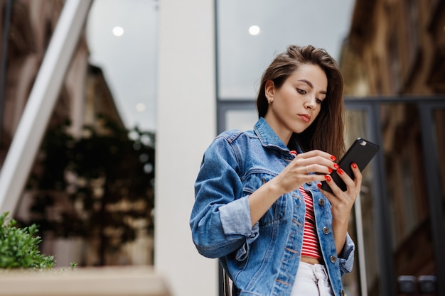 Giovane donna che manda un sms all'aperto