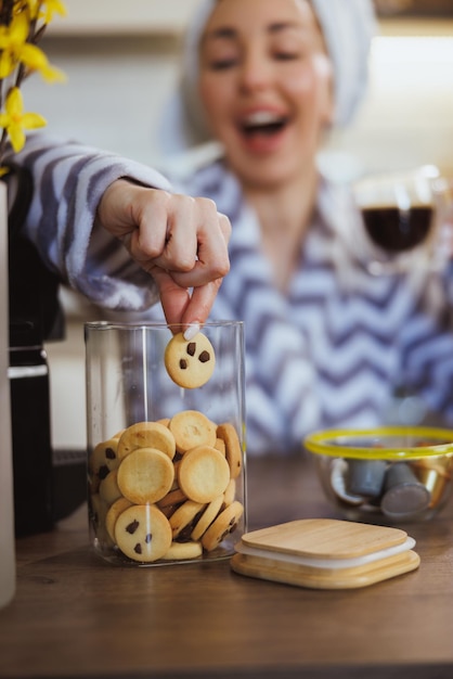 Giovane donna che mangia biscotti freschi fatti in casa e si gode il caffè del mattino a casa.