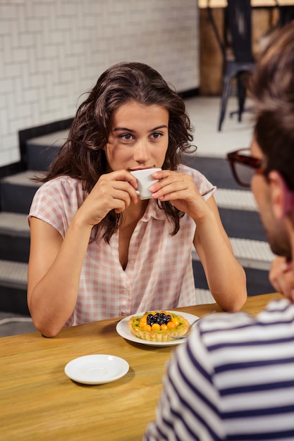 Giovane donna che mangia caffè in self-service