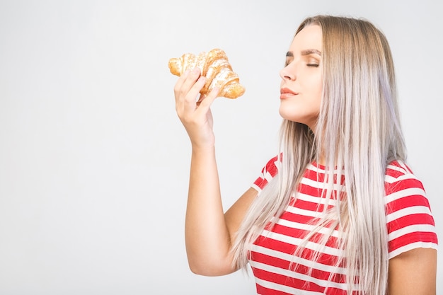 Giovane donna che mangia croissant, pausa caffè