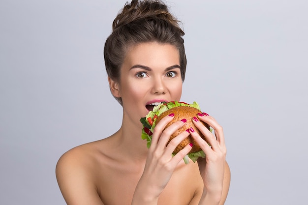 Giovane donna che mangia hamburger fatto di verdure, concetto di alimentazione sana