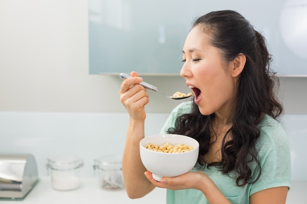 Giovane donna che mangia i cereali in cucina