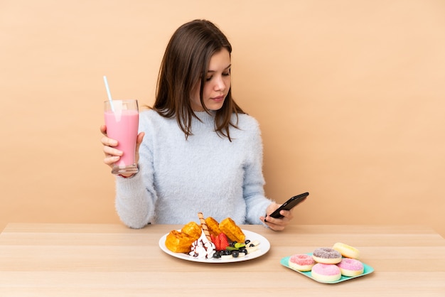 Giovane donna che mangia i waffle