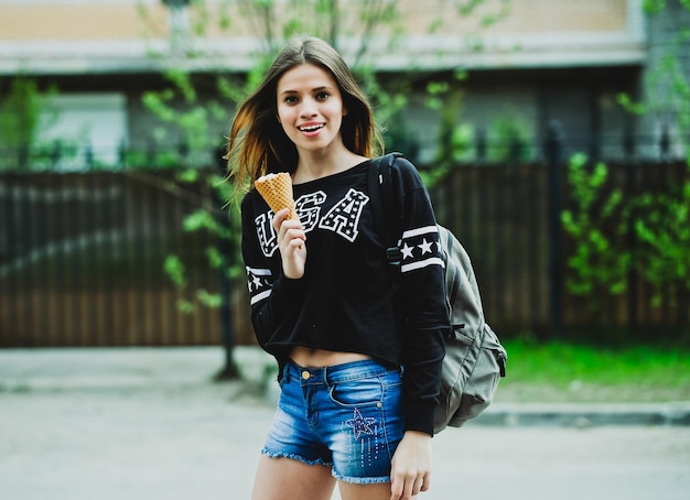 Giovane donna che mangia il gelato giornata di sole all'aperto, vicino alla grande casa