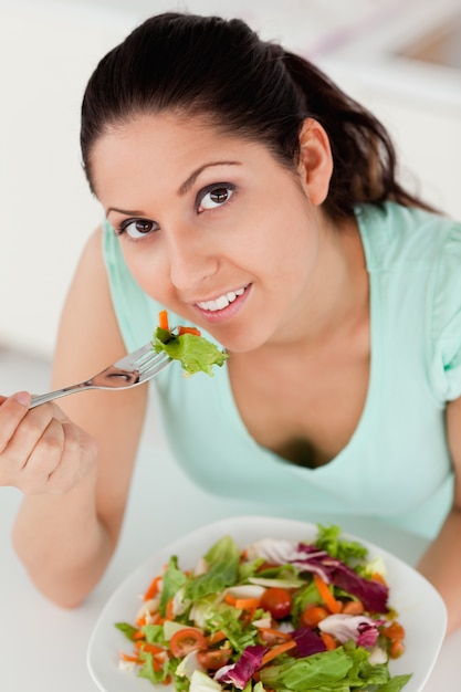 Giovane donna che mangia insalata