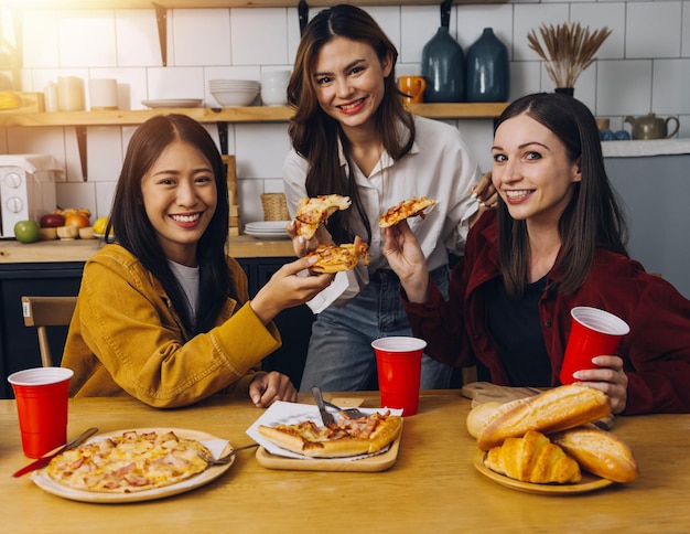 Giovane donna che mangia pizza e ride mentre si siede con i suoi amici in un ristorante Gruppo di amici che si divertono mentre mangiano e bevono al bar