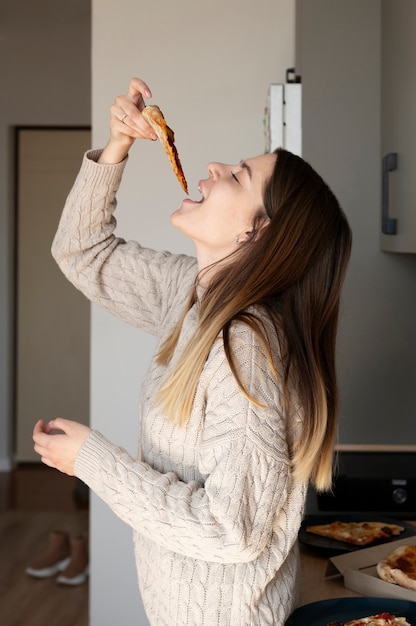 Giovane donna che mangia pizza