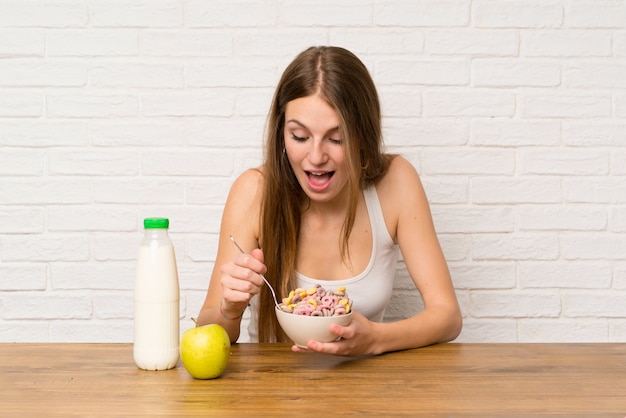 Giovane donna che mangia prima colazione con la ciotola di cereali