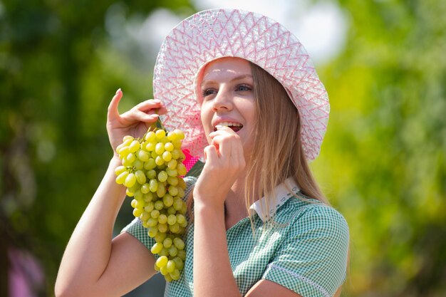Giovane donna che mangia uva fresca Ritratto di donna sorridente caucasica attraente che mangia uva donna i