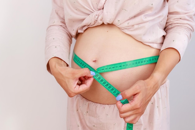 Giovane donna che misura la sua pancia incinta con un nastro di centimetro Preparazione per il parto Ragazza pancia grande avanzata gravidanza sana