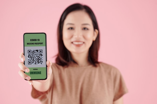 Giovane donna che mostra smartphone con codice qr dopo aver ricevuto un vaccino contro il coronavirus