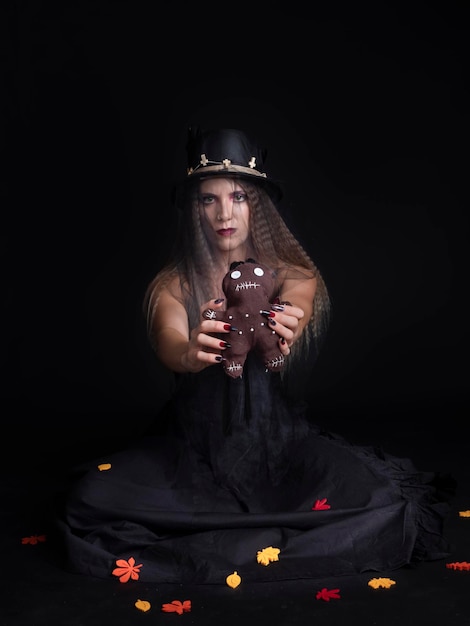 Giovane donna che mostra una bambola voodoo ad Halloween