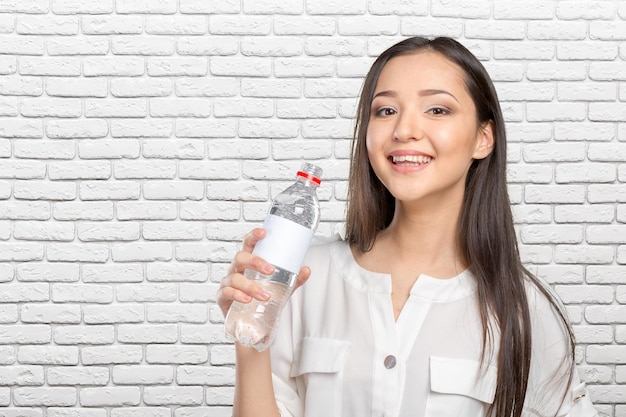 Giovane donna che mostra una bottiglia d'acqua