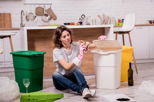 Giovane donna che ordina immondizia alla cucina. Concetto di riciclaggio. Zero sprechi