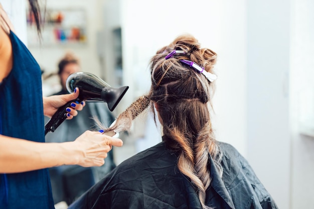 Giovane donna che ottiene bella acconciatura nel salone di capelli.