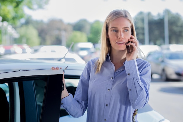 Giovane donna che parla al cellulare mentre è in piedi vicino all'auto