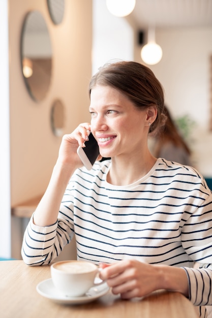 Giovane donna che parla al telefono al caffè