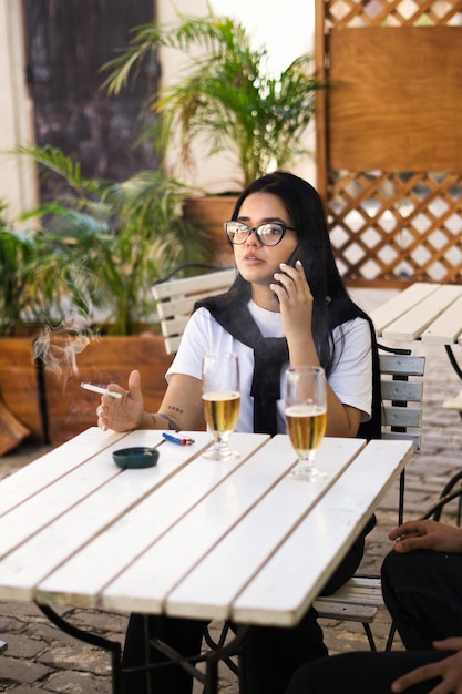 giovane donna che parla al telefono, fuma e beve una birra rinfrescante, Lifestyle, blogger, outdoo