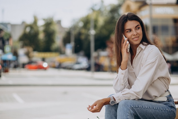 Giovane donna che parla al telefono fuori strada