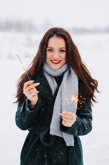 Giovane donna che pattina sul ghiaccio all'aperto su uno stagno in una gelida giornata invernale con le stelle filanti in mano