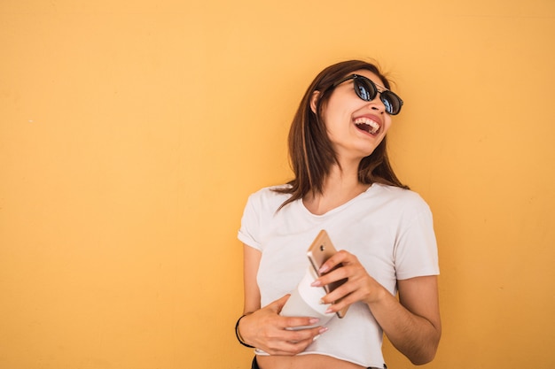 Giovane donna che per mezzo del suo telefono cellulare.