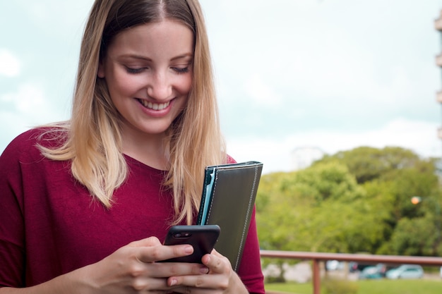 Giovane donna che per mezzo del suo telefono cellulare.