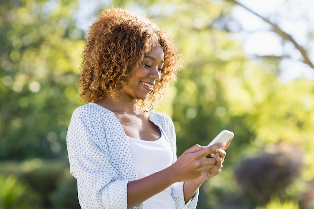 Giovane donna che per mezzo del telefono cellulare