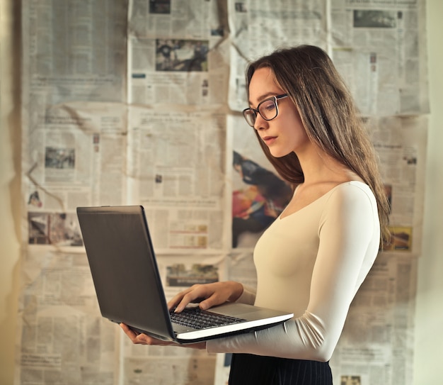 Giovane donna che per mezzo di un computer portatile