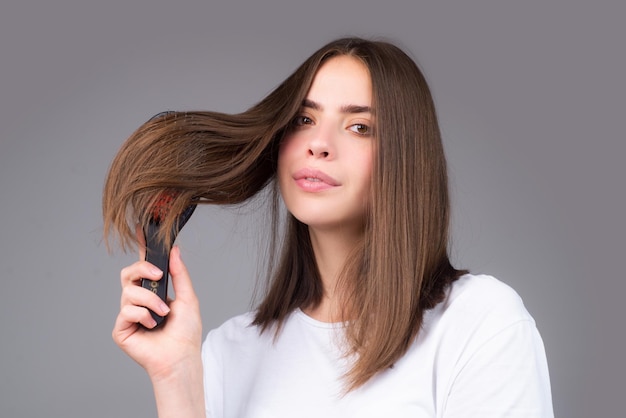 Giovane donna che pettina capelli lucidi sani e naturali isolati su cura dei capelli di bellezza dello studio