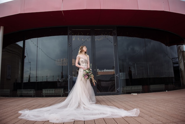 Giovane donna che posa in un vestito da sposa bianco