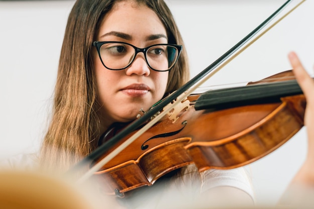 Giovane donna che pratica il violino a casa guardando le dita sulla tastiera del violino