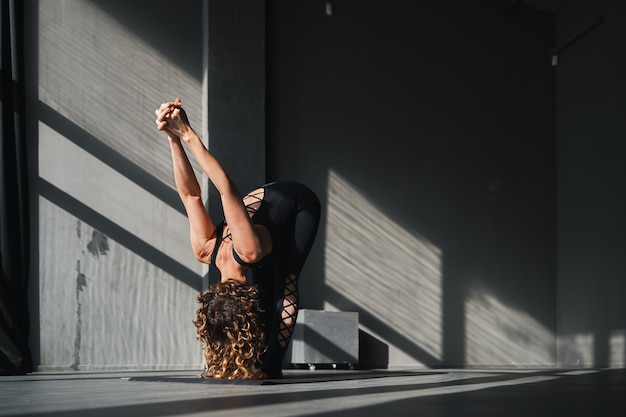 Giovane donna che pratica lo yoga pone in uno sfondo urbano in giornata di sole