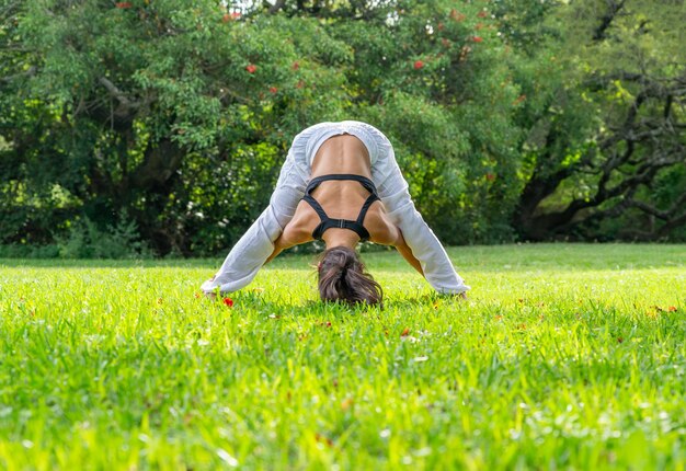 Giovane donna che pratica yoga facendo Prasarita Padottanasana posa in un concetto di ParkWellness