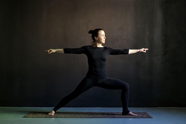 Giovane donna che pratica yoga Posa del guerriero Virabhadrasana